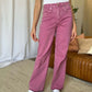 Woman wearing RFM Full Size High Rise Garment Dye Wide Leg Jeans in pink, paired with a white top and white sneakers