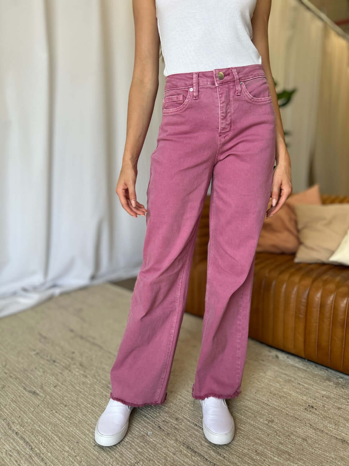 Woman wearing RFM Full Size High Rise Garment Dye Wide Leg Jeans in pink, paired with a white top and white sneakers