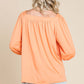 Back view of a woman wearing a trendy Square Neck Puff Sleeve Top in orange paired with light blue denim shorts.