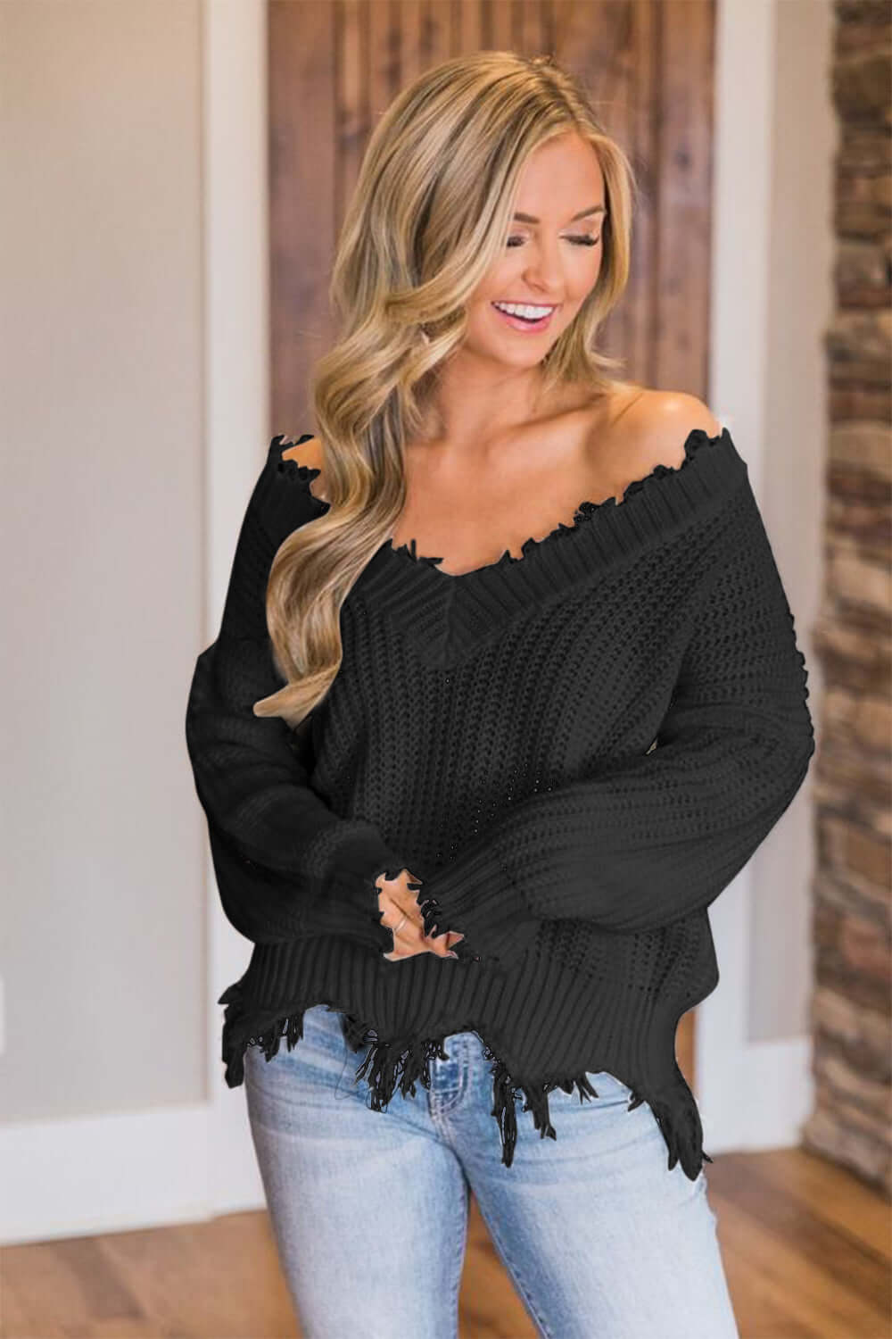 Woman wearing Bella Road frayed hem dropped shoulder sweater, black knit, casual chic look.