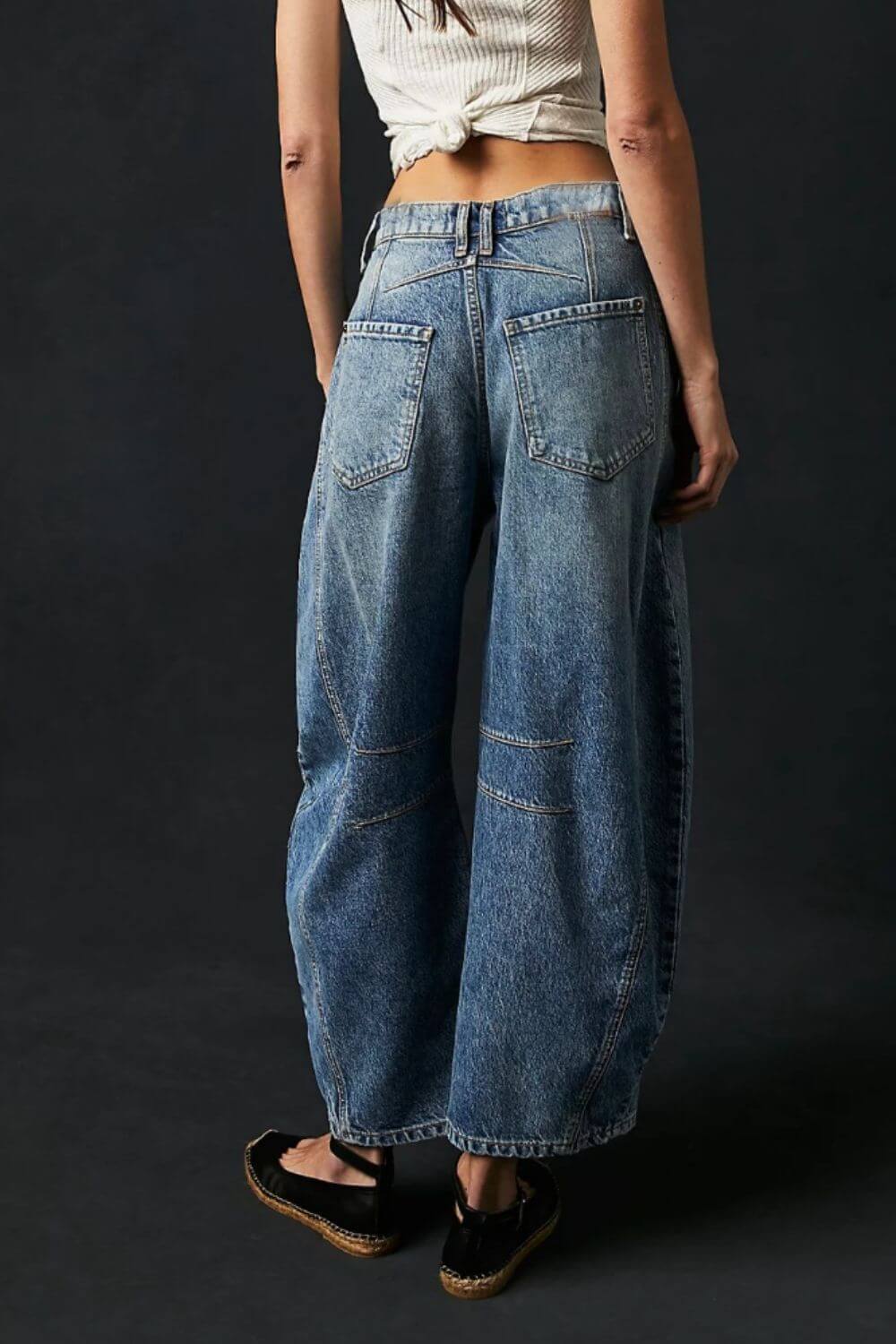 Back view of woman wearing wide leg jeans with pockets, featuring buttoned design and no stretch material, 95% cotton and 5% polyester.