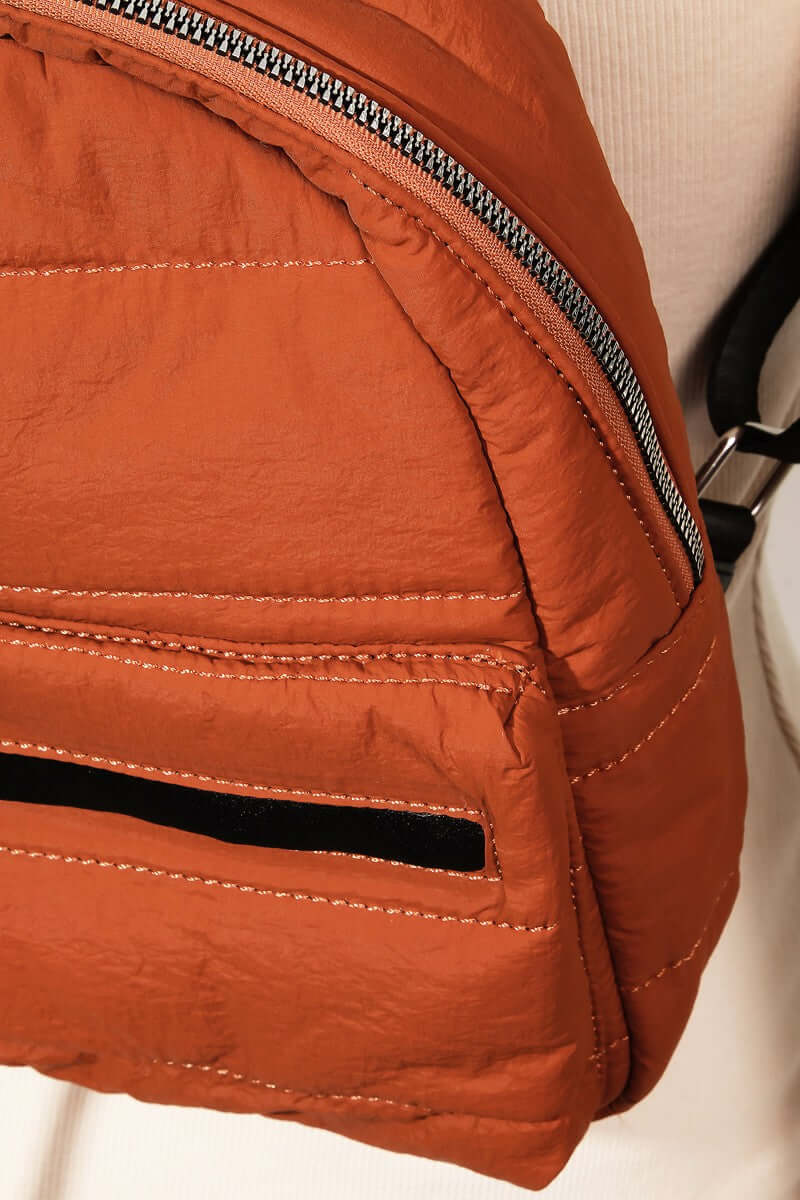 Close-up of an orange nylon backpack showcasing its durable material and stylish zipper detail. Perfect for travel!