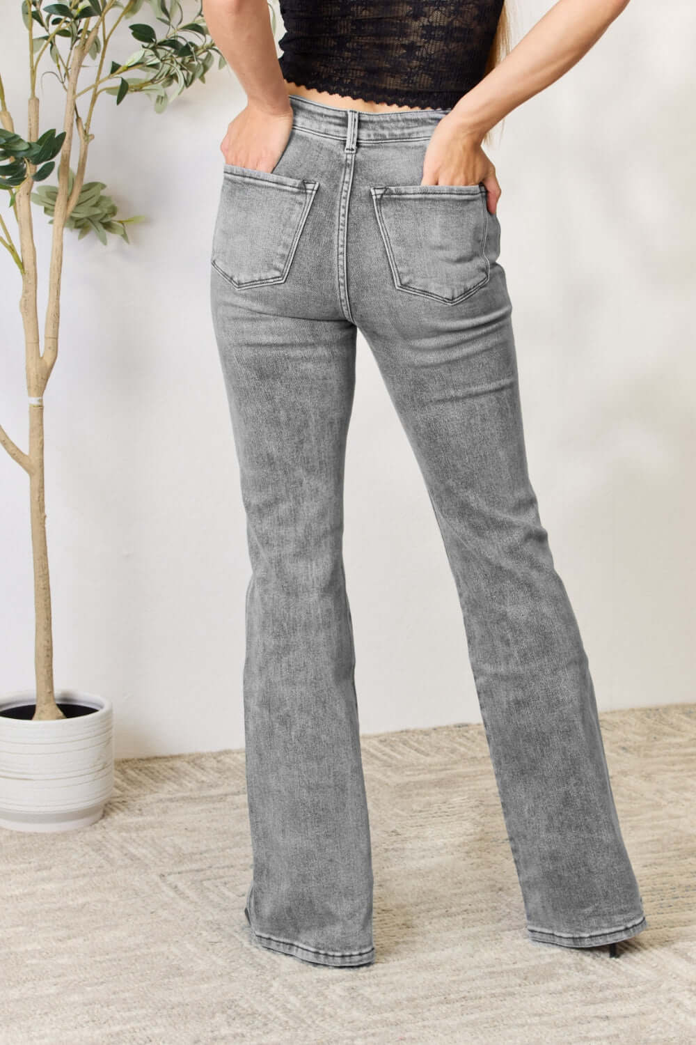 High Waist Slim Flare Jeans in grey, featuring back pockets, shown on model standing with hands in pockets, styled with a black lace top.