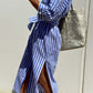 Woman wearing Bella Road Tied Button Up Three-Quarter Sleeve Dress in blue and white stripes, carrying a gold tote bag.