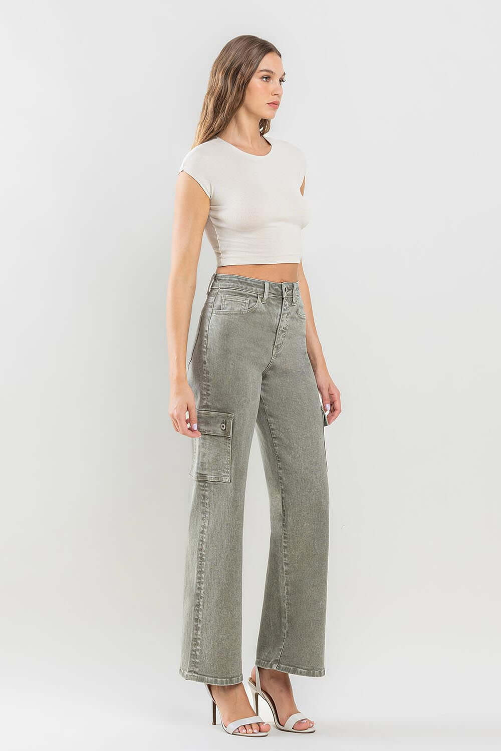 Woman wearing 90s super high rise cargo jeans with ultra-high waist and loose fit, paired with a crop top and heels.