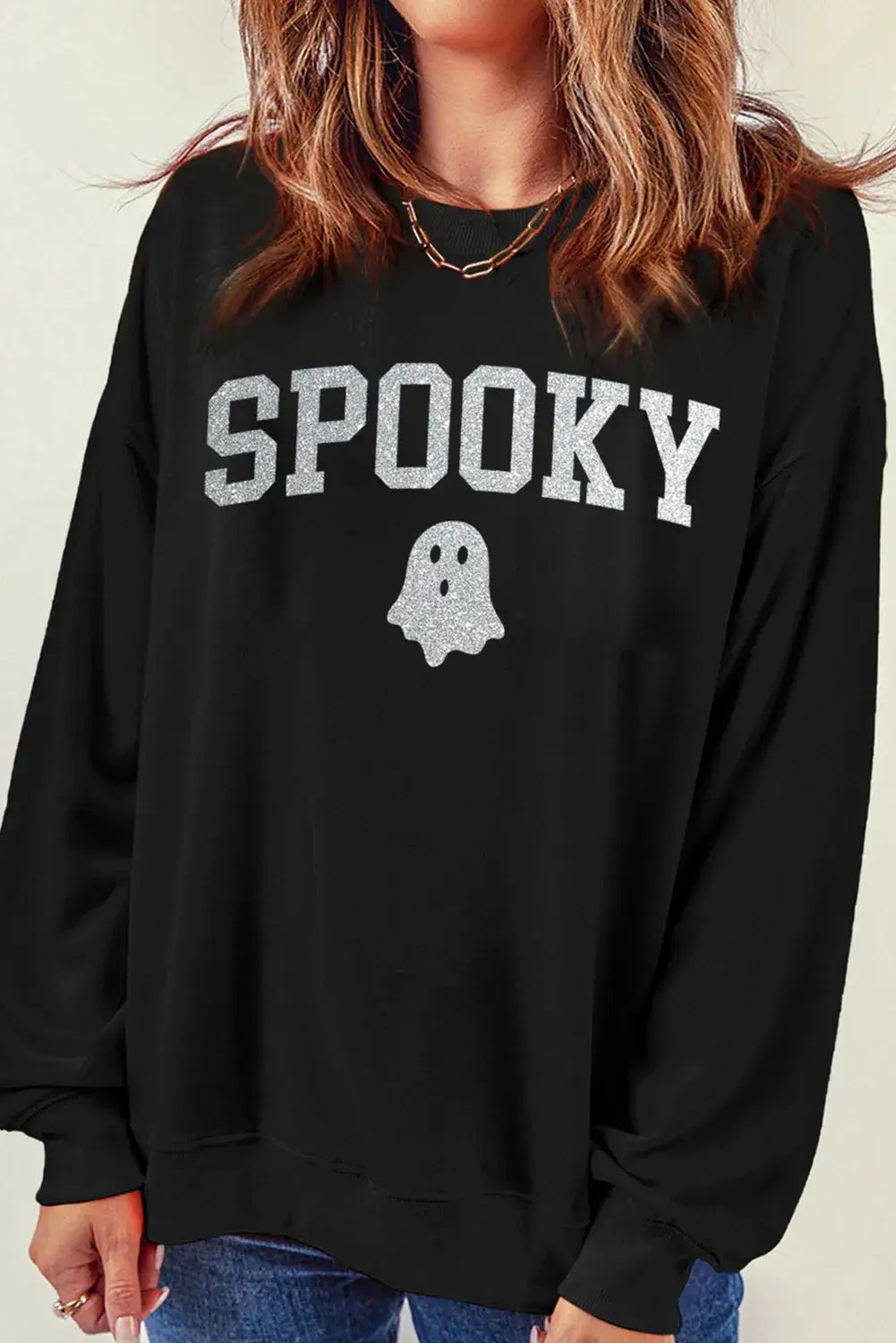 Woman wearing Bella Road SPOOKY round neck long sleeve sweatshirt with ghost design, perfect for cozy and spooky occasions.