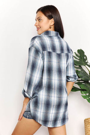 Woman wearing a plaid dropped shoulder shirt with a collared neckline and long sleeves, showcasing the back view of the shirt.