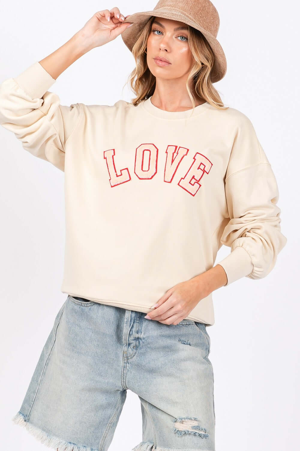 Woman wearing LOVE Path Applique Drop Shoulder Sweatshirt with a round neckline and dropped shoulders, standing in a relaxed pose.