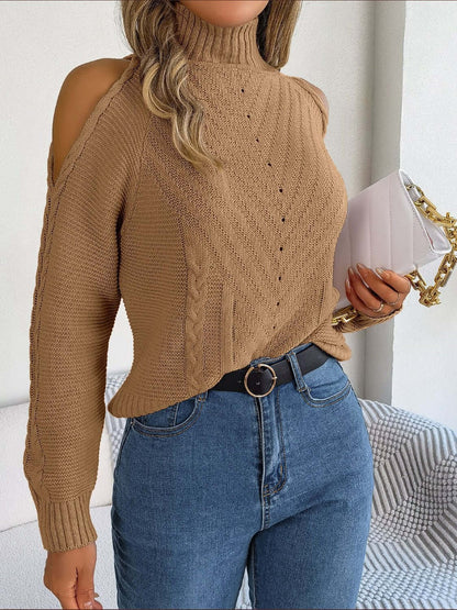 Woman wears Bella Road Cable-Knit Turtleneck Cold Shoulder Sweater with jeans, holding a white clutch. Cozy and trendy fashion style.