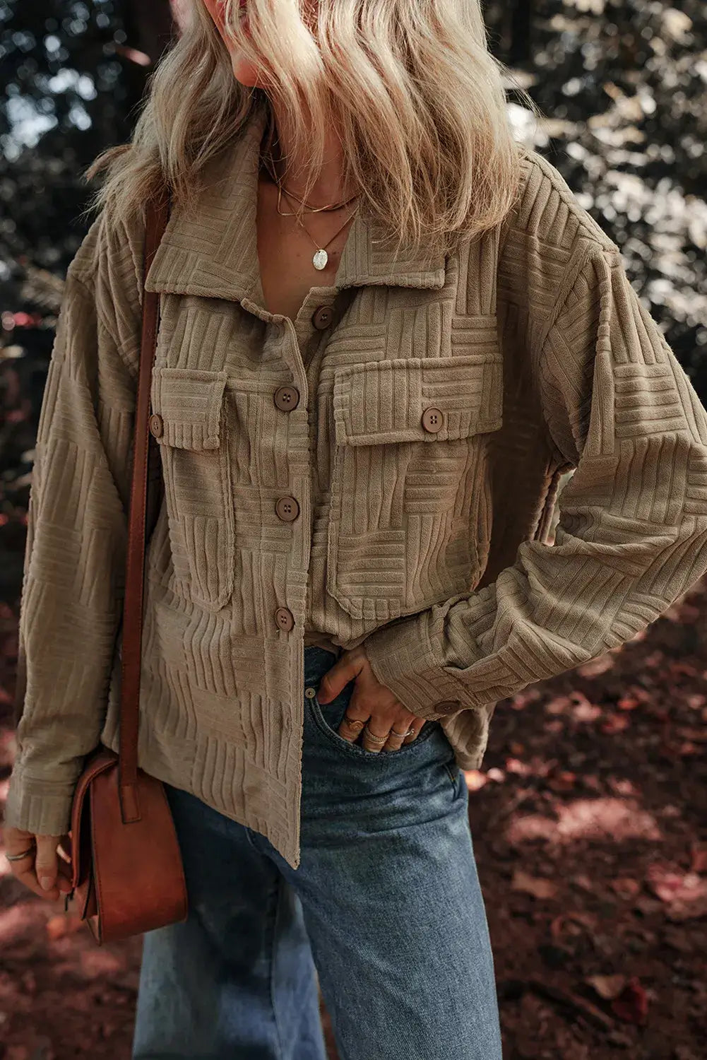 Woman wearing textured pocketed collared neck long sleeve shacket with blue jeans, outdoors.