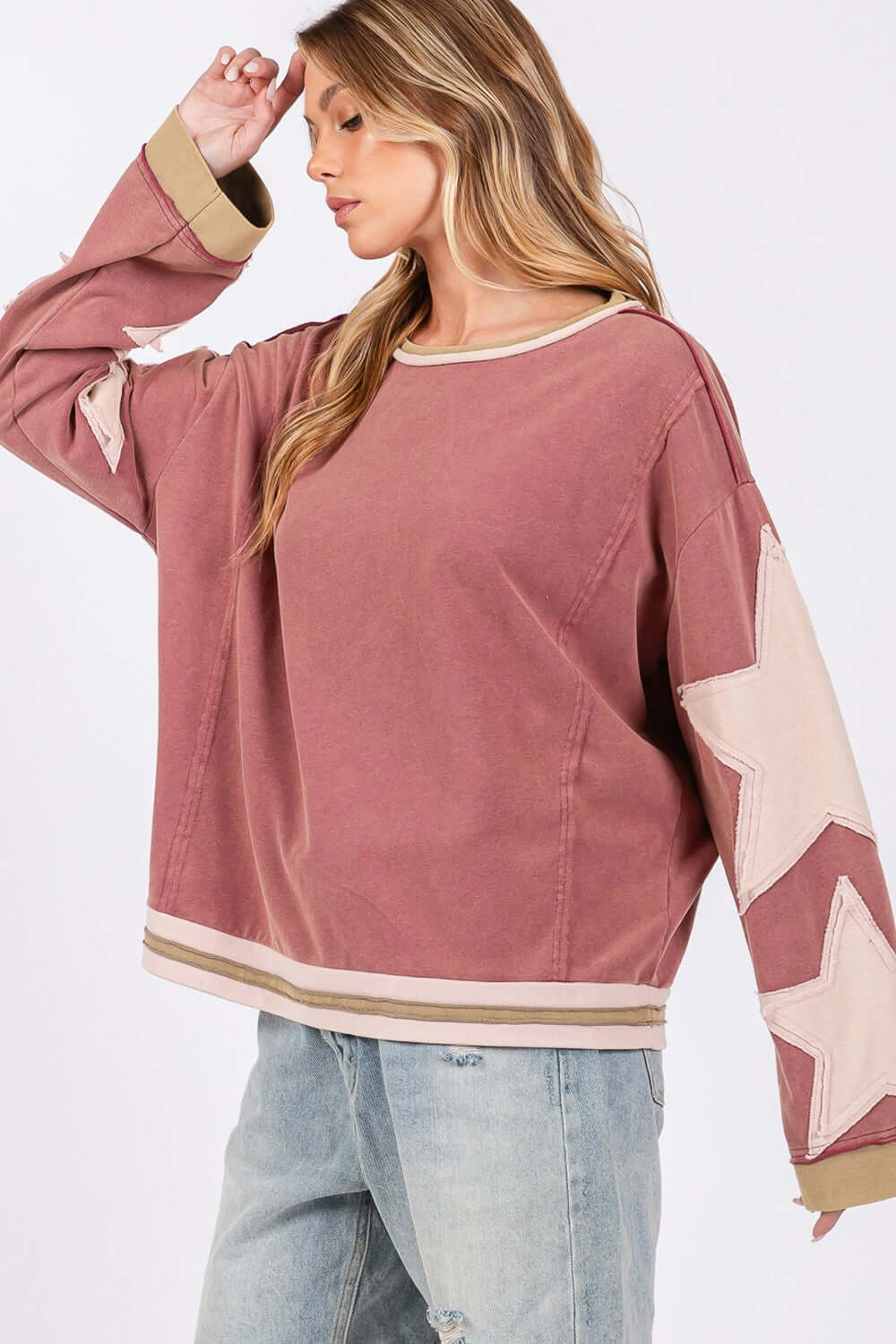 Woman wearing SAGE + FIG French Terry Star Applique Patch Sweatshirt, casual chic style, cozy pink top with star detailing.