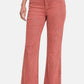 Stylish pink bootcut jeans with frayed hem, embodying trendy vintage charm and a flattering silhouette.