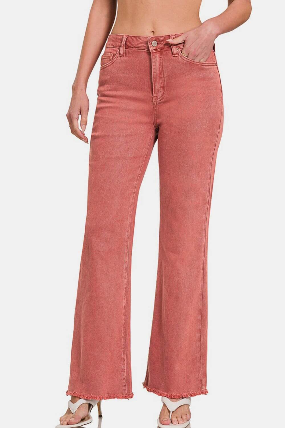 Stylish pink bootcut jeans with frayed hem, embodying trendy vintage charm and a flattering silhouette.