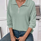 Woman wearing mint green striped half zip long sleeve t-shirt with jeans in a casual indoor setting.