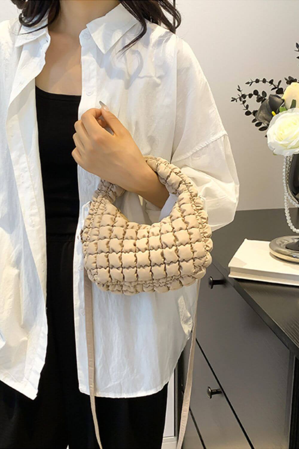 Woman holding Bella Road Quilted Puffy Crossbody Bag with removable strap, polyester material, in a stylish room setting.