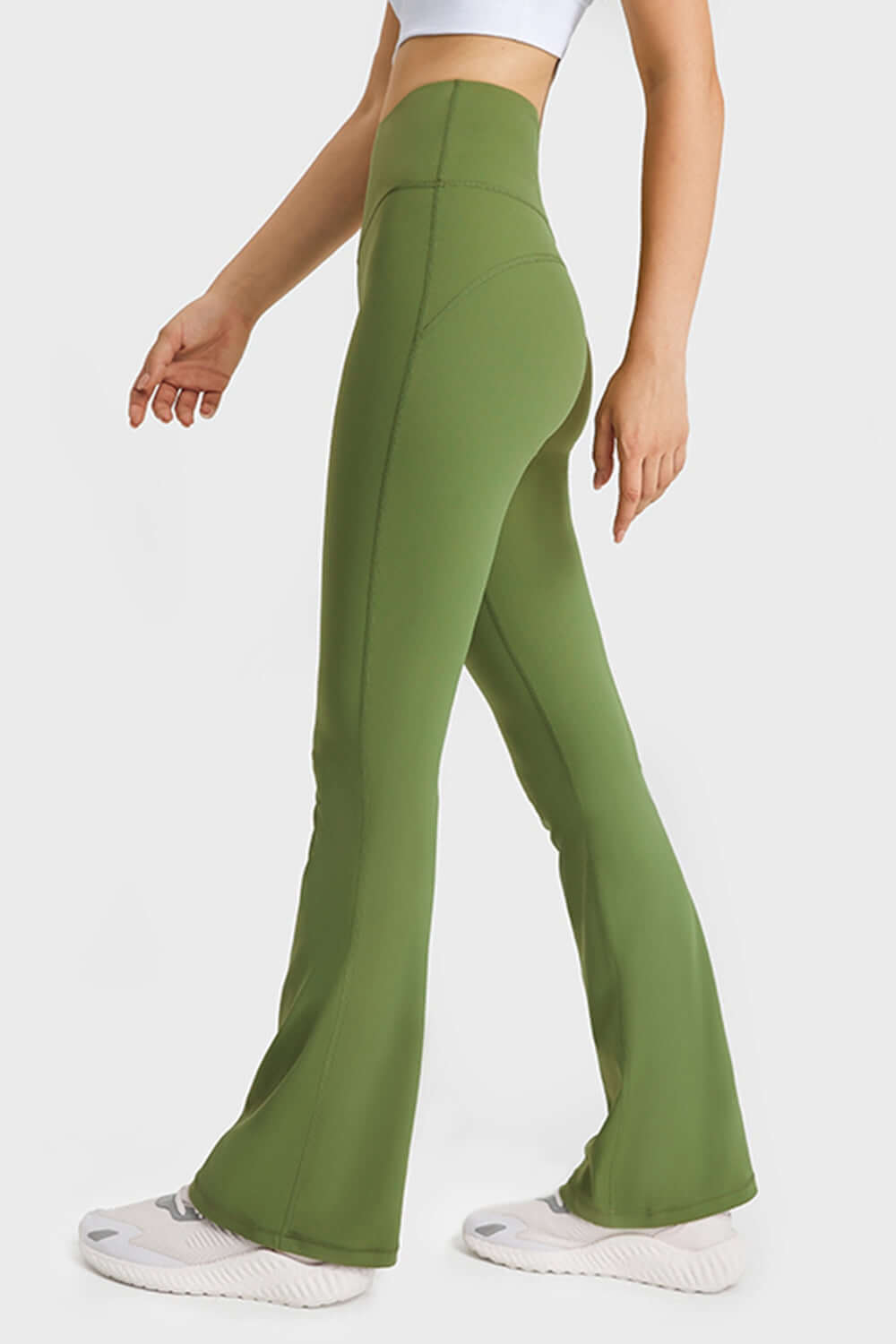 Model showcasing Millennia Elastic Waist Flare Yoga Pants in green, designed for comfort and flexibility in workouts.