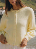 Woman wearing a cozy pastel yellow button-down long sleeve cardigan by Bella Road, perfect for chilly days.