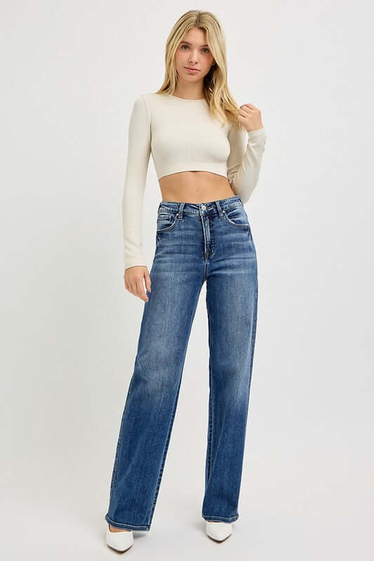 Model showcasing RISEN Full Size Tummy Control High Rise Jeans with a cropped top and stylish white heels.