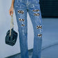 Woman wearing distressed slightly stretchy jeans with skeleton pattern and pockets, holding a black purse.