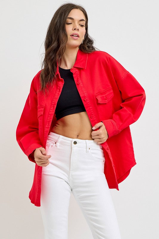 Woman wearing a red button-down long sleeve denim shacket over a black top and white jeans, showcasing a stylish casual look.