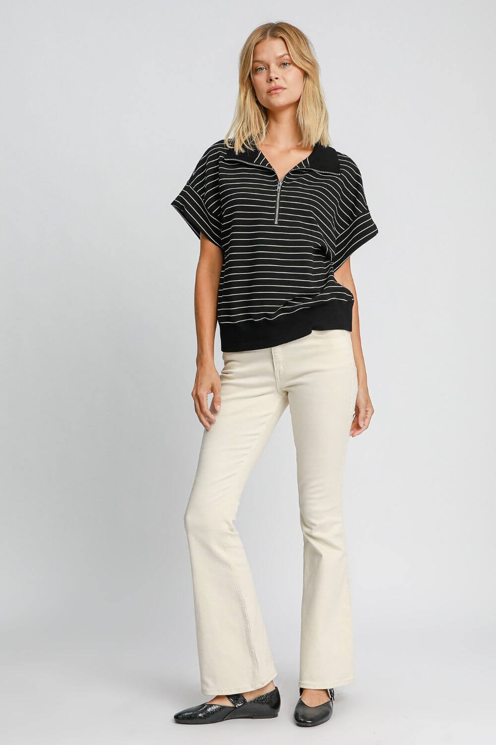 Stylish model wearing Umgee striped half zip short sleeve sweatshirt with flared cream pants against a light background.