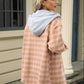 Woman wearing Bella Road Drawstring Plaid Long Sleeve Hooded Jacket in pink and gray, standing outdoors