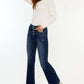 Woman wearing Kancan Mid Rise Button Fly Flare Jeans with a white top and sneakers, showcasing trendy denim fashion.