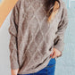 Woman wearing Bella Road Diamond Round Neck Long Sleeve Sweater in soft fabric with unique diamond pattern and classic round neck design.