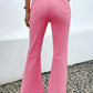 Back view of pink distressed raw hem bootcut jeans with slightly stretchy fit, paired with a white top.