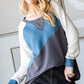 Woman wearing HOPELY color block long sleeve T-shirt with bold blue and gray design, paired with black shorts, showcasing a casual style.