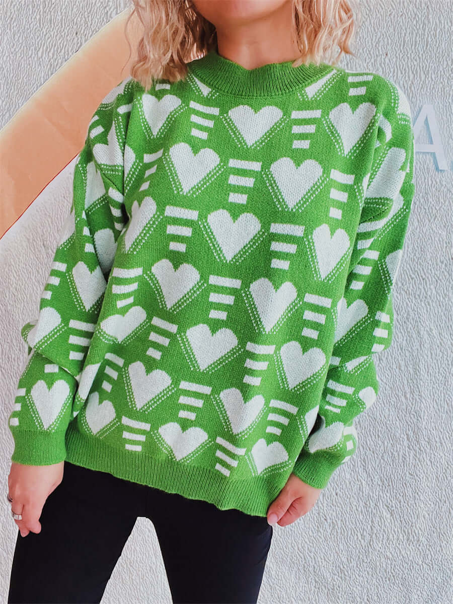 Woman wearing a green Bella Heart sweater with white heart contrast pattern and dropped shoulders for a cozy and chic look