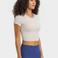 Model wearing the Millennia Round Neck Short Sleeve Cropped Sports T-Shirt in beige, styled with high-waisted leggings.