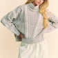 Cozy gray cable-knit turtleneck sweater with dropped shoulders, exuding stylish warmth for colder seasons.