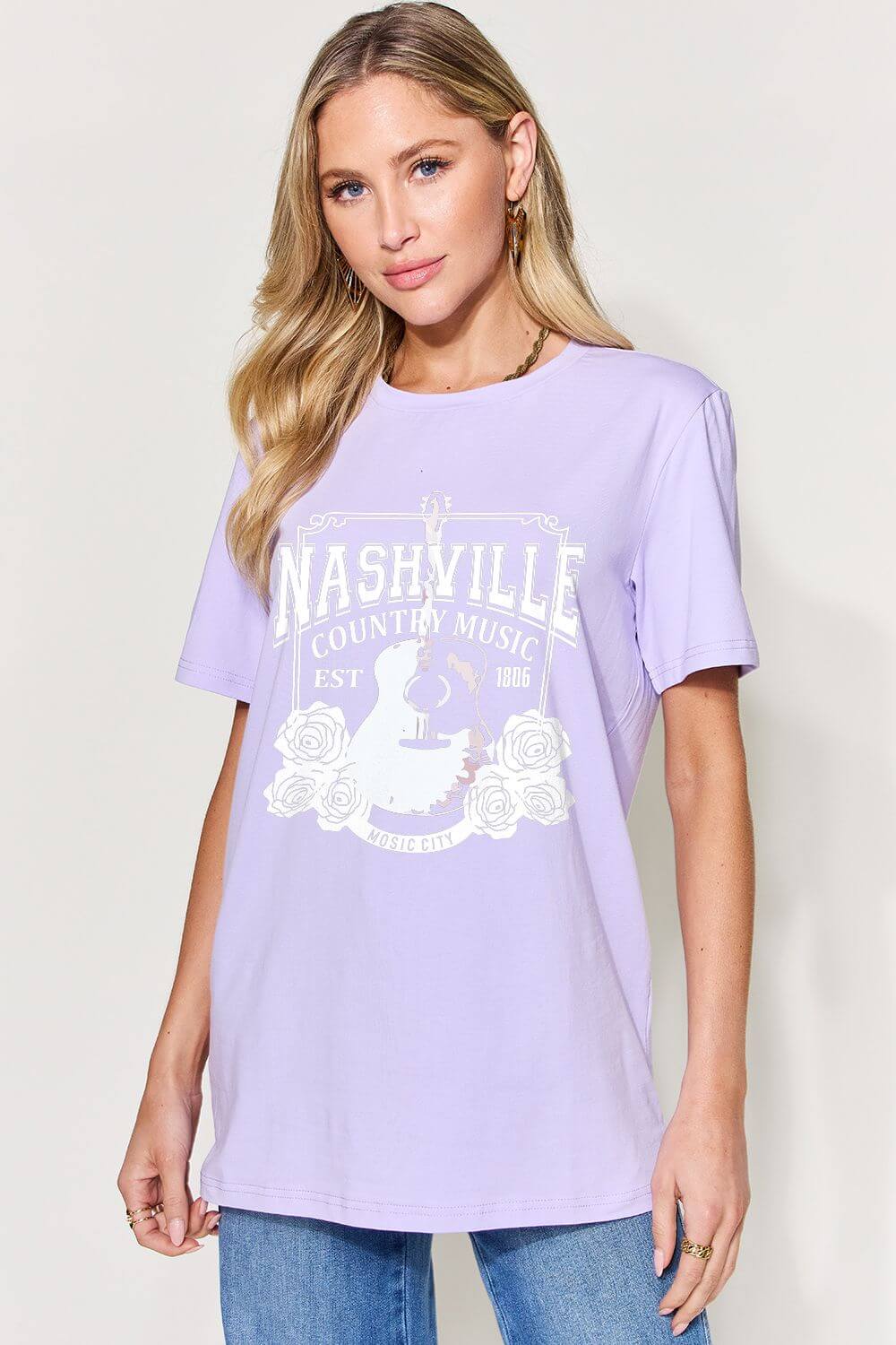 Woman wearing a purple graphic round neck short sleeve T-shirt with Nashville country music design.