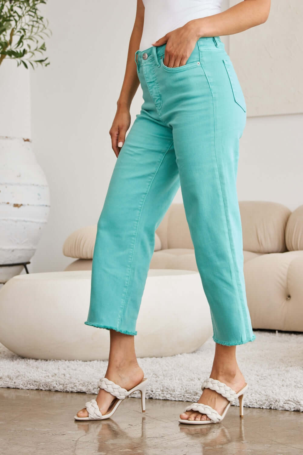 Woman wearing Crop Chloe Full Size Tummy Control High Waist Raw Hem Jeans in turquoise from RFM Jeans.