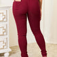 Woman wearing maroon skinny jeans from YMI Jeans, featuring rear pockets and a stretchy, curve-accentuating fit.