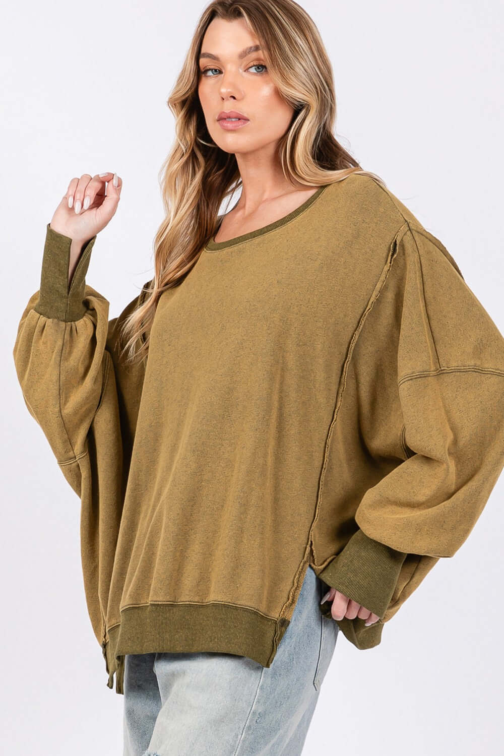 Woman wearing Mineral Wash Side Slit Oversized Sweatshirt with wide scoop neck and exposed seams for a trendy, edgy look.