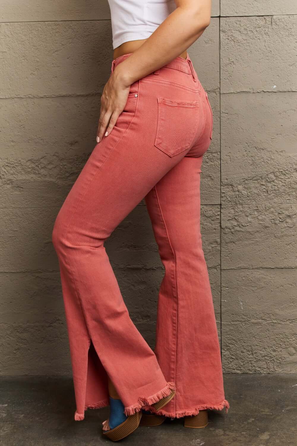 Woman wearing Bailey High Waist Side Slit Flare Jeans in coral, showing side slit details and flattering high-rise fit. Risen Jeans.