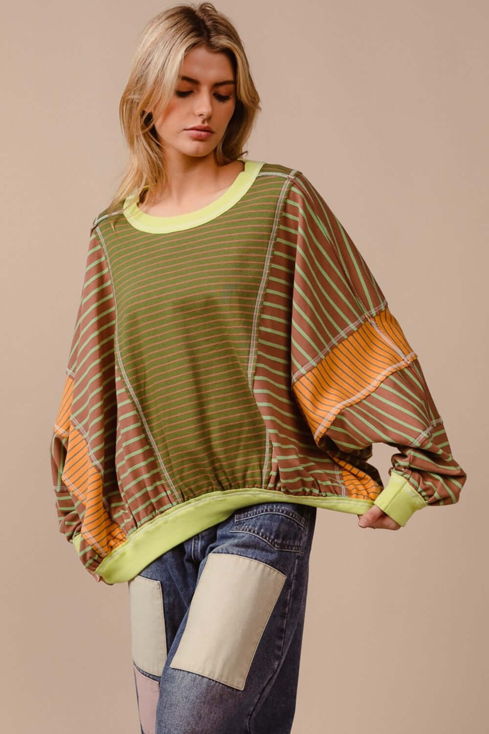 Trendy Color Block Striped Round Neck Sweatshirt with bold colors, perfect for casual outings or lounging, paired with patchwork jeans.