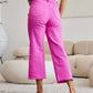 Woman wearing pink RFM Jeans Tummy Control High Waist Raw Hem, back view with white top and heels in a stylish interior.