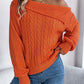 Woman wearing Bella Road Cable-Knit One Shoulder Long Sleeve Sweater in orange paired with blue jeans.