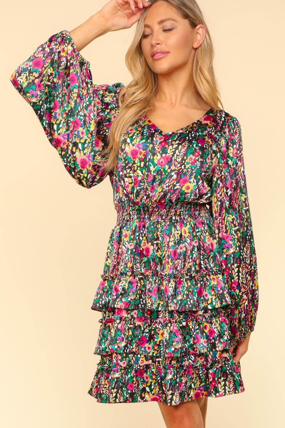 Woman wearing a vibrant floral layered dress with long sleeves and V-neckline, highlighting its flowy and feminine design.