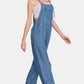 Woman in washed adjustable strap wide leg denim overalls, styled for a casual and chic look.