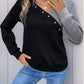 Stylish black and gray sweatshirt with decorative buttons, perfect for a fashionable look.