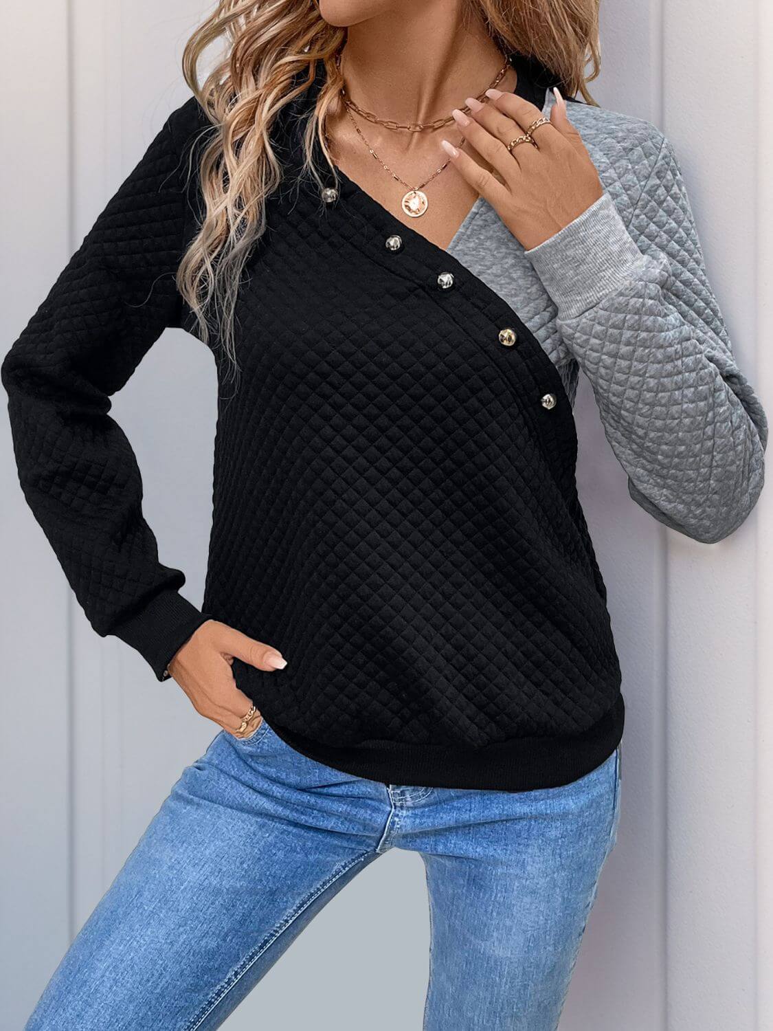 Stylish black and gray sweatshirt with decorative buttons, perfect for a fashionable look.