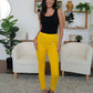 Woman modeling FAM-FAM High Waist Skinny Pants in vibrant yellow with decorative buttons, modern living room setting.