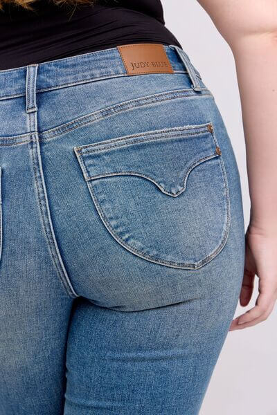 Back view of Judy Blue mid rise tummy control vintage wash jeans, showcasing flattering fit and retro charm.