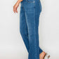 Woman showcasing Cat's Whiskers Mid Rise Ankle Jeans with a chic side pose and stylish sandals, highlighting classic denim fashion.