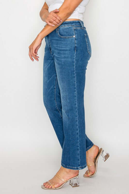 Woman showcasing Cat's Whiskers Mid Rise Ankle Jeans with a chic side pose and stylish sandals, highlighting classic denim fashion.