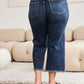 Back view of model wearing high waist raw hem distressed jeans with tummy control in a living room setting.